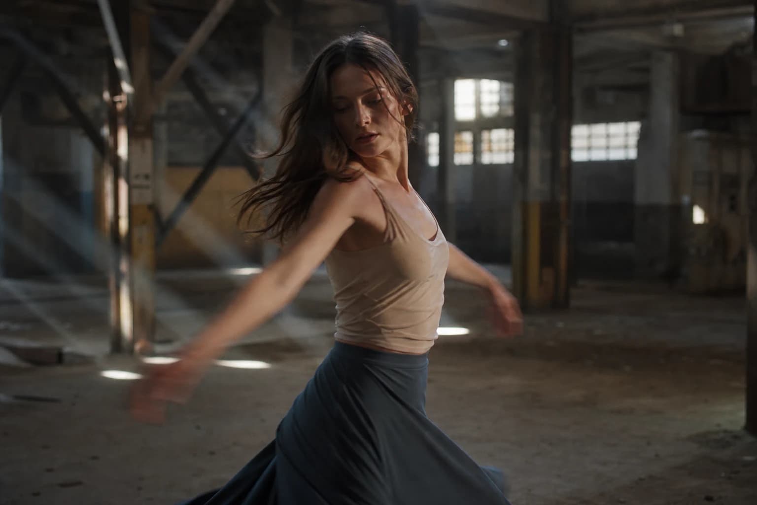 Danseuse en rotation lente dans entrepôt, lumière volumétrique, référence mouvement Kling 3